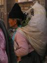 Lady on the street with bag of vegetables for sale.